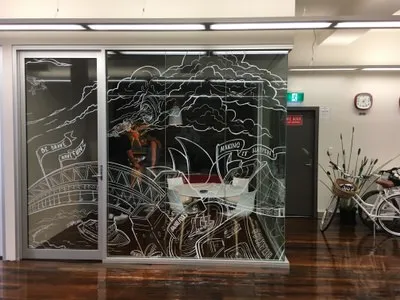White line art mural on glass office walls illustrating the Sydney Harbour Bridge, Opera House, and clouds