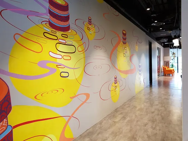 Hallway mural of glowing yellow abstract orbs with stacked patterned rings and swirling pink ripples