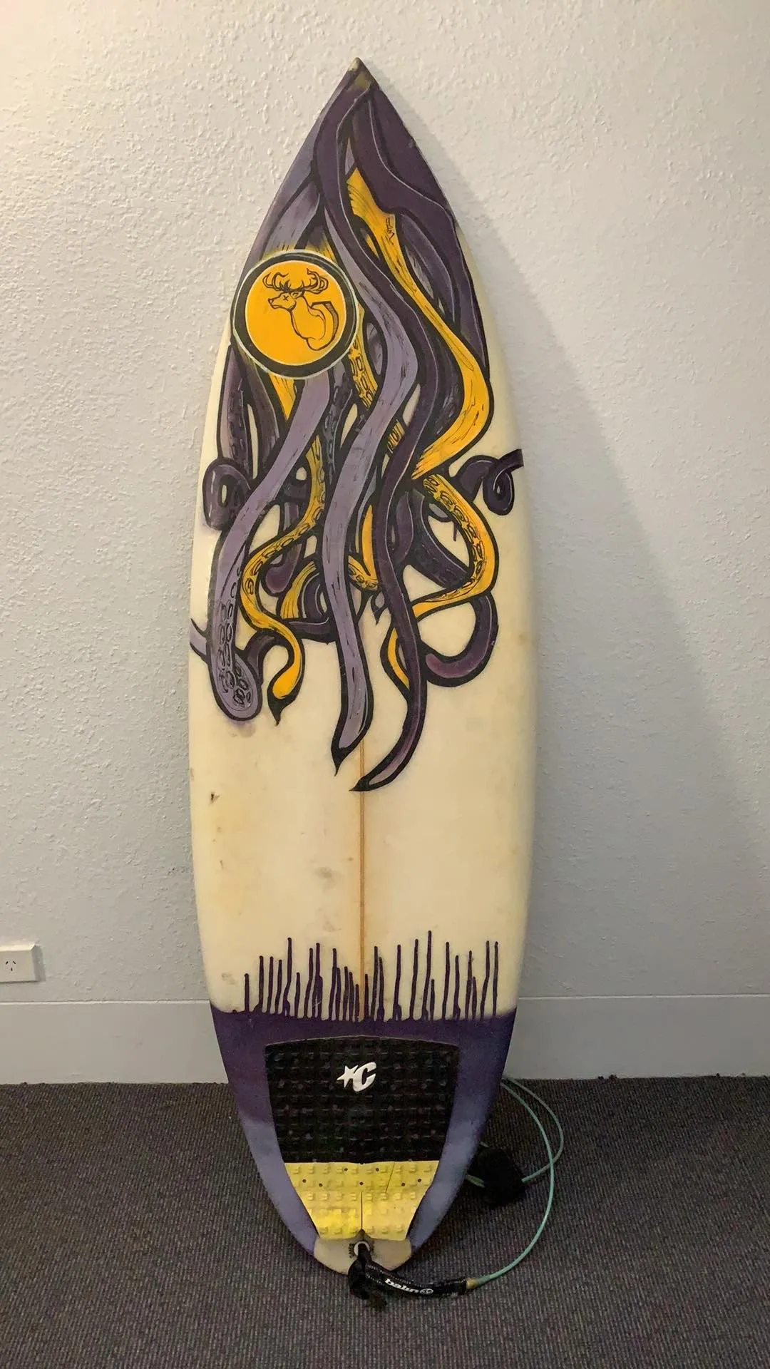 Painted surfboard featuring intertwined purple and yellow octopus tentacles on the upper half