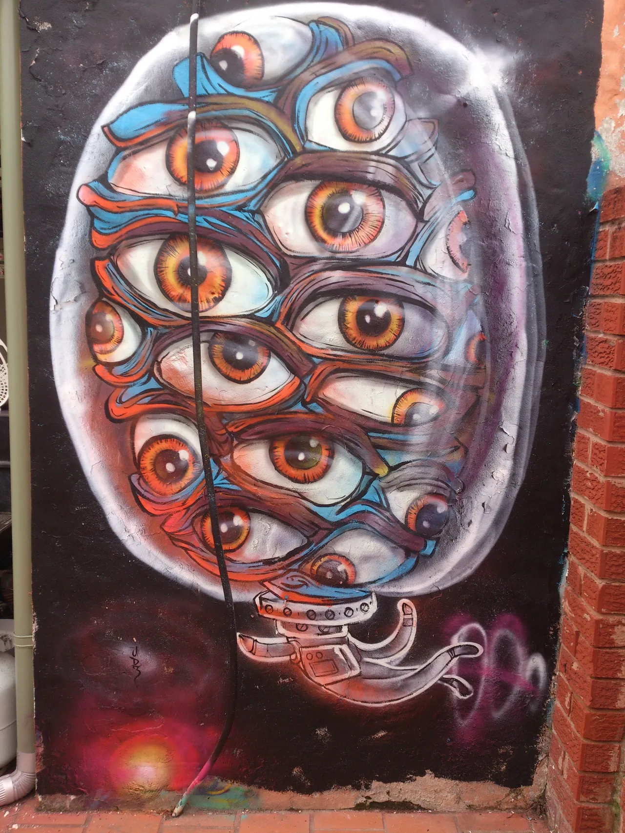 Mural of a psychedelic oval of stacked eyes with a floating spaceman on a dark, cosmic background