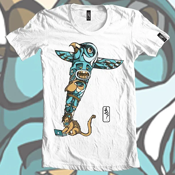 White t-shirt featuring a bold illustration of a blue totem pole resting on the head of a monkey using a laptop