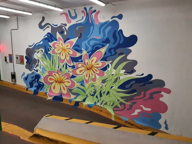 Carpark mural of three stylized pink and yellow flowers with green leaves against flowing abstract blue and grey shapes