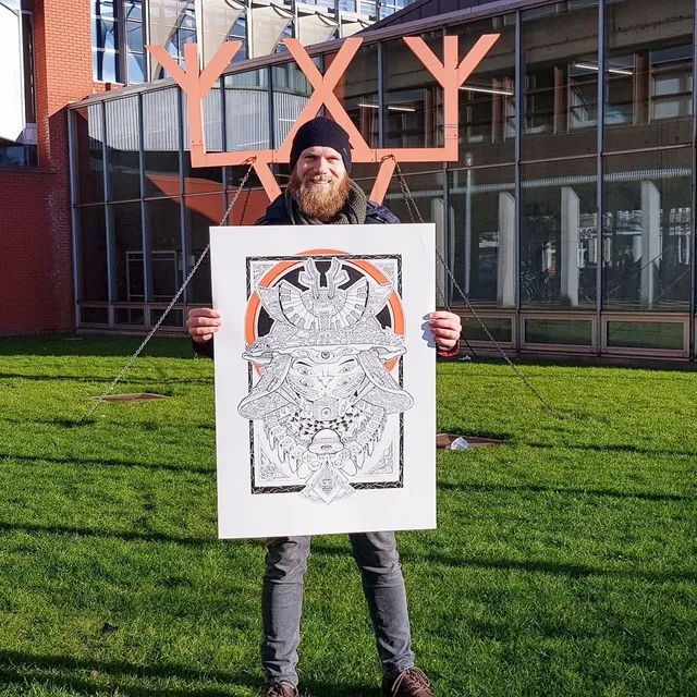 Man outdoors holding a large custom poster featuring a detailed black and orange line drawing of a samurai face mask