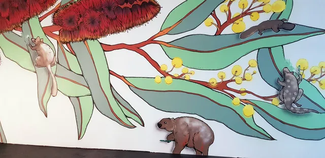 Mural of Australian animals like a wombat, platypus, and possums among large bottlebrush and wattle flowers