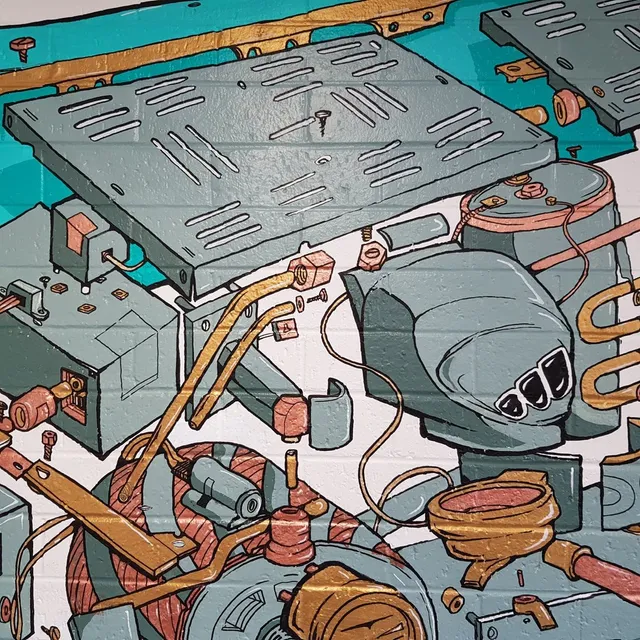 Mural on brick showing deconstructed espresso machine parts including a portafilter and copper pipes