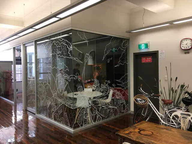 White line mural of a dense Sydney cityscape drawn across the glass corner walls of an office meeting room