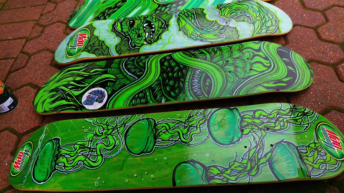 Four hand-painted skateboards with bold green psychedelic designs of a monster, tentacles, and jellyfish