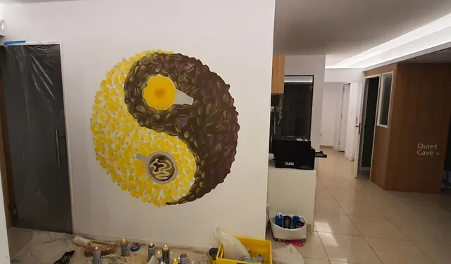 Mural of a yin-yang symbol made of painted coffee beans and yellow dots, featuring a coffee cup and a yellow circle