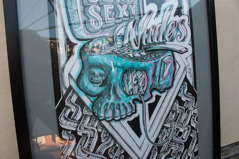 Framed illustration of a mechanical skull with an anaglyph 3D effect below the text Dead Sexy Nudes