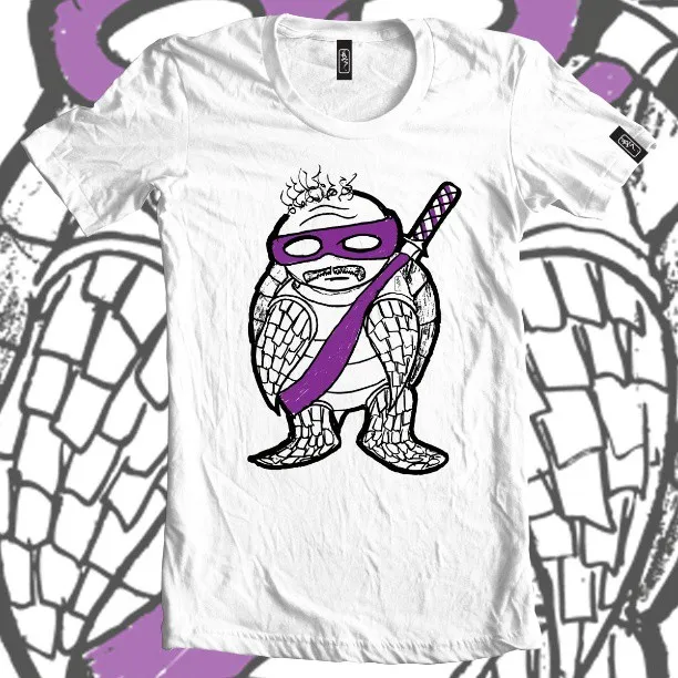 White t-shirt featuring a bold line illustration of a balding ninja turtle character with a mustache and purple mask
