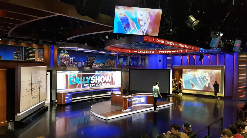 The Daily Show with Trevor Noah TV studio set with screens displaying logos and graphics