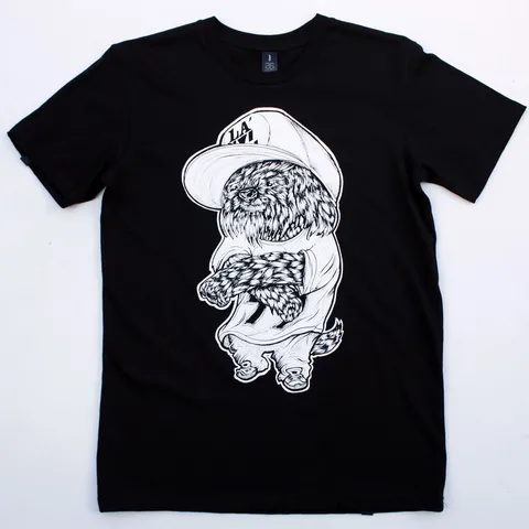 Black t-shirt with a white line drawing of a fluffy dog wearing a large cap and baggy shirt with arms crossed