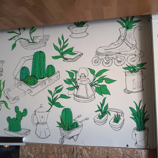 Mural of bright green plants growing from bold black line drawings of a rollerblade, suitcase, and moka pot