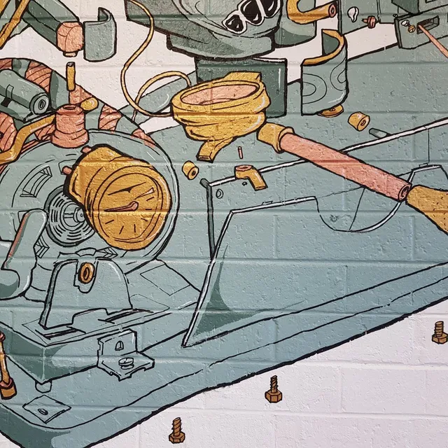 Mural on white brick showing an exploded view of espresso machine parts including a pressure gauge and portafilter