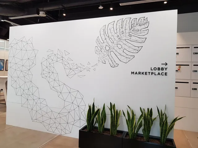 Geometric black line mural on a white wall showing a wireframe monstera leaf breaking apart into triangles