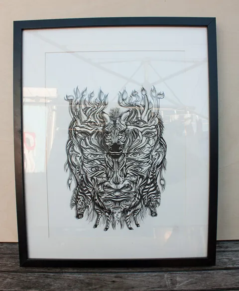 Framed ink drawing of a symmetrical psychedelic mask composed of zebra heads, multiple eyes, and bold linework