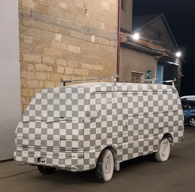 Van covered entirely in a grey and white checkerboard pattern including the windows