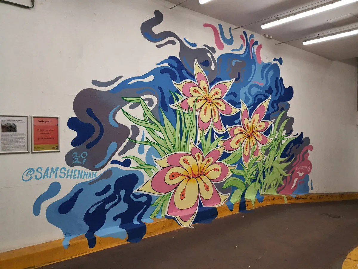 Mural of large stylized pink and yellow flowers with green leaves set against flowing, abstract blue and grey shapes