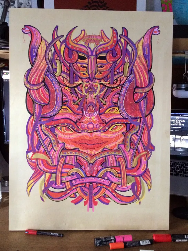 Marker drawing on a wooden panel of a symmetrical psychedelic face intertwined with pink and purple tentacles