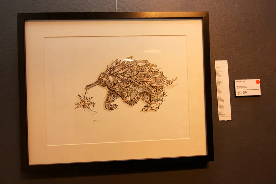 Framed ink drawing of a stylized echidna with a star hanging from its snout, displayed on a dark gallery wall