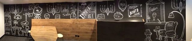 Panoramic white line art mural on a black wall depicting typography, chandeliers and an armchair behind wooden partitions