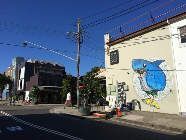 Mural on a street corner building depicting a blue shark character wearing green striped shorts and yellow flippers