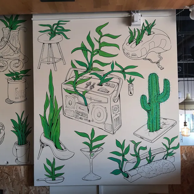 Mural of bright green plants sprouting from black line drawings of a boombox, high heel, smartphone, and helmet