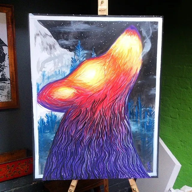 Canvas painting on an easel of a howling wolf with a fiery color gradient against a starry night sky and snowy mountains