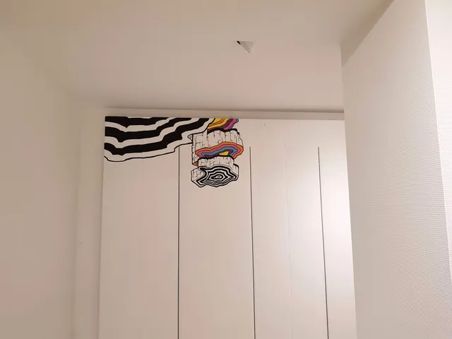 Mural on white panels featuring black and white wavy lines morphing into layered 3D blocks with bright rainbow colors