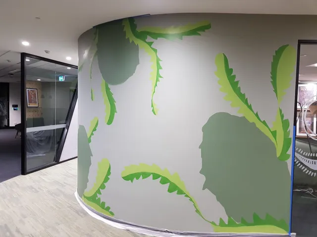Unfinished mural on a curved office wall featuring large jagged green leaf designs and blue painter's tape