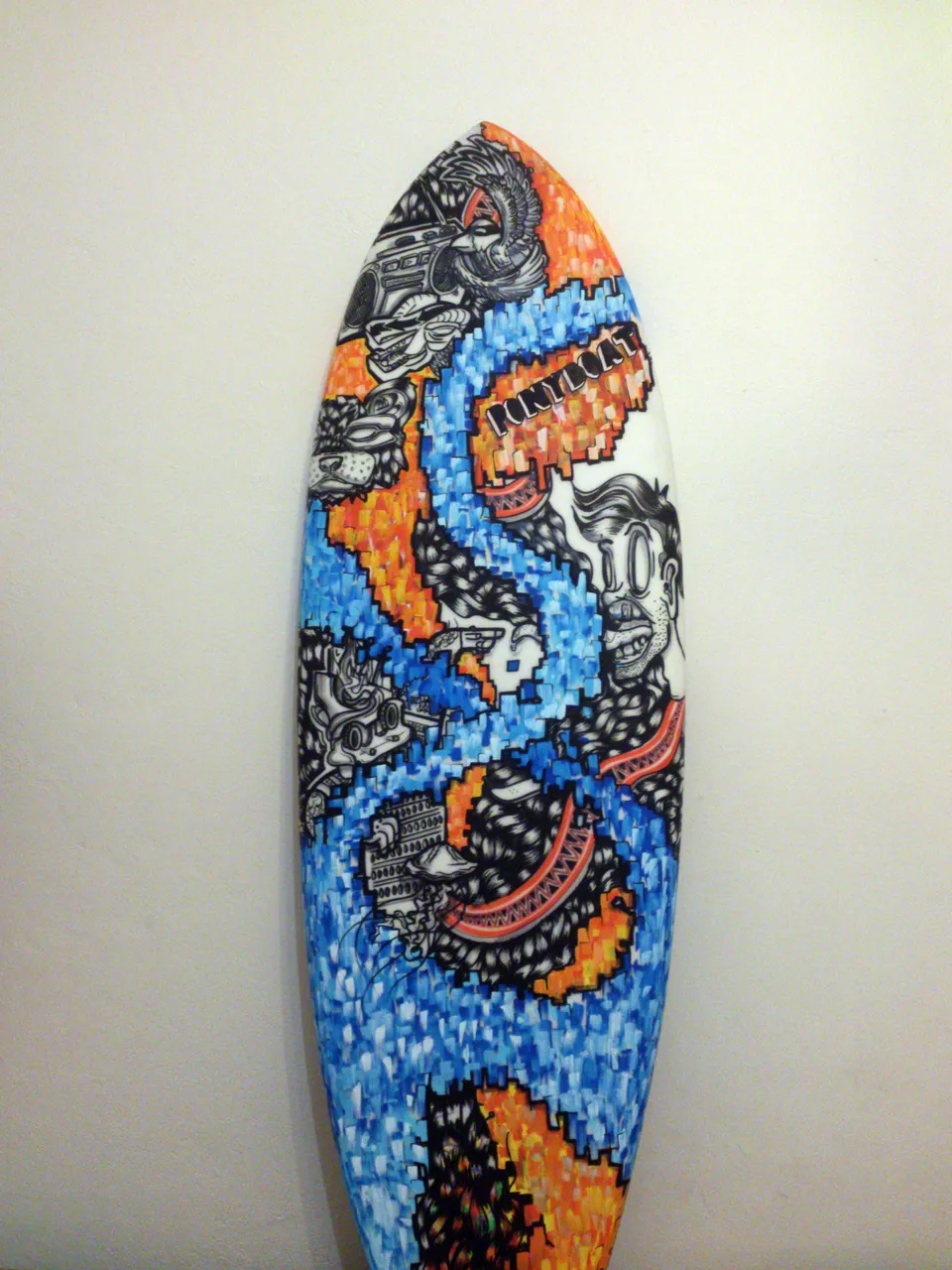 Painted surfboard featuring a winding blue pixelated path, orange accents, and black-and-white psychedelic illustrations
