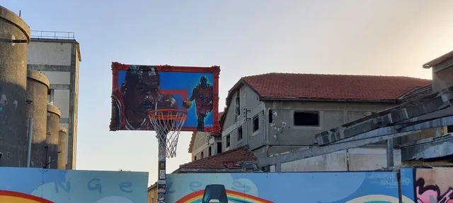 Hand-painted basketball backboard depicting Michael Jordan within an ornate red frame, mounted on an outdoor hoop