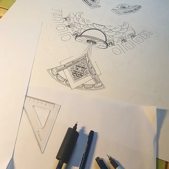 In-progress ink drawing of a UFO and 30th birthday message on paper, alongside drafting pens and a ruler