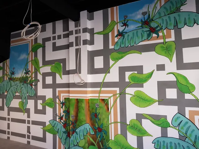 Wall mural of green coffee plants and tropical leaves overlaid on a grey geometric pattern and painted blue sky panels
