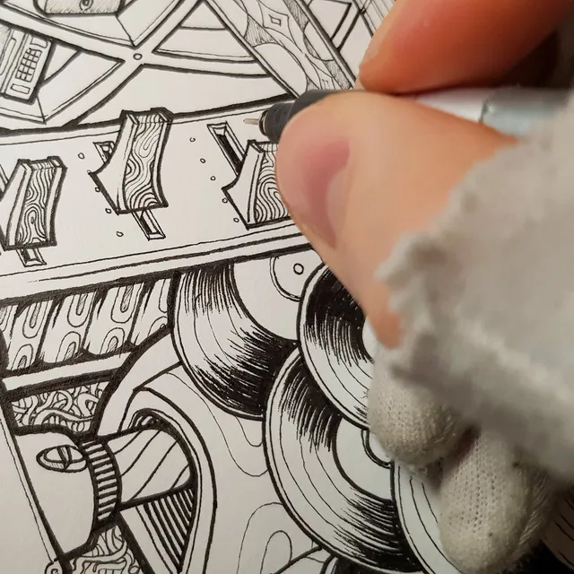 Close-up of a hand drawing intricate black ink line work on a poster with a fine-liner pen