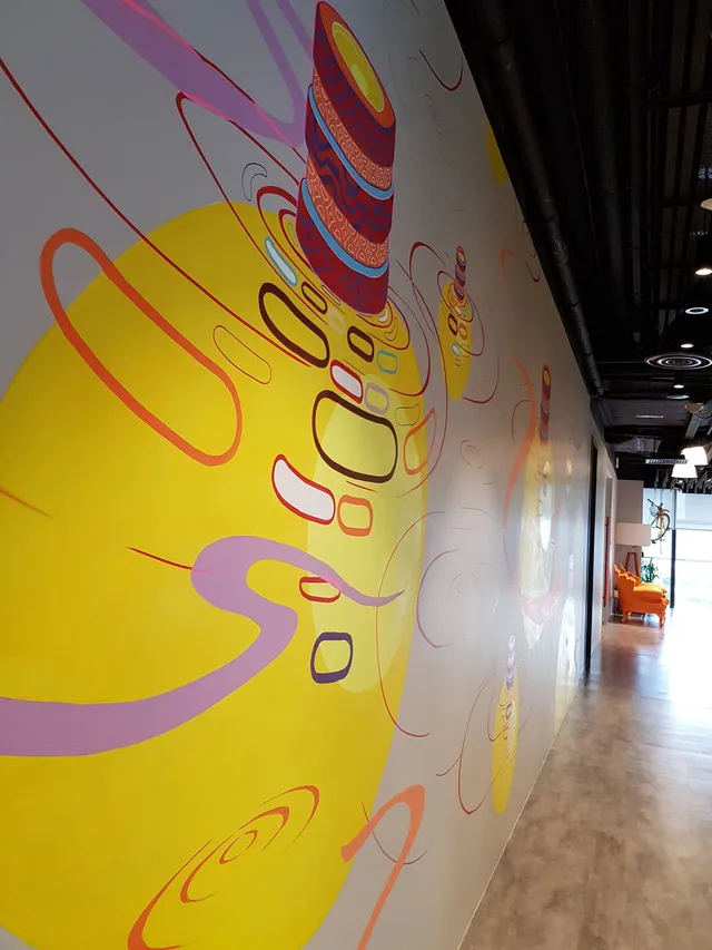 Abstract hallway mural of a large yellow sphere, floating geometric outlines, purple swirls and a patterned totem