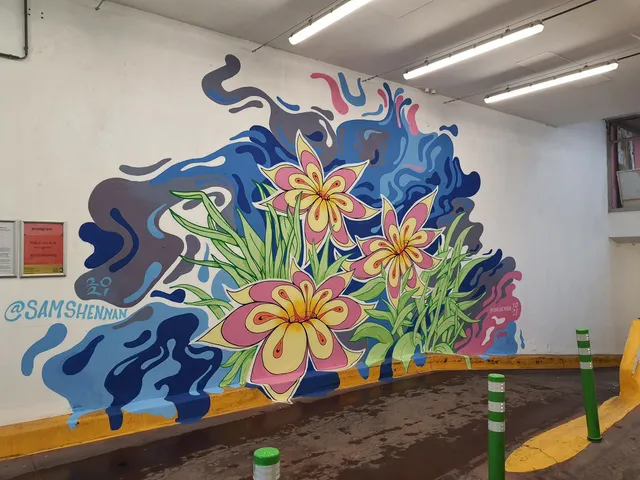 Carpark mural of three stylized pink and yellow flowers set against abstract flowing blue and purple shapes