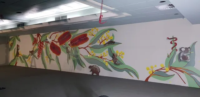 Long indoor mural depicting Australian native flora and fauna, including banksia, wattle, a wombat, and a koala