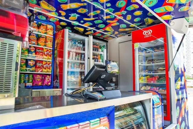 Mobile store interior featuring a custom ceiling wrap with colorful food illustrations on a blue background