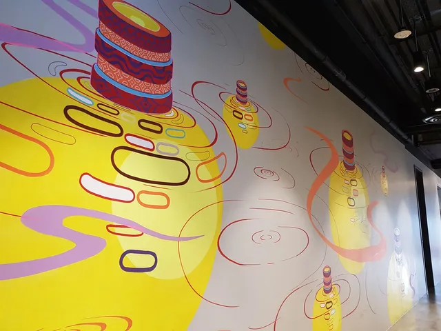Indoor wall mural of stacked patterned cylinders creating stylized red ripples over large glowing yellow circles