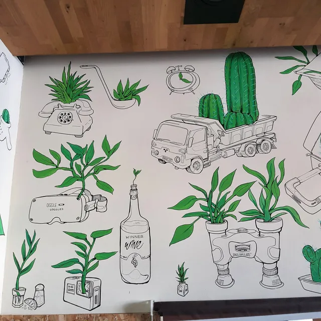 Wall mural of green plants growing out of bold line drawings of objects like a dump truck, rotary phone, and VR headset