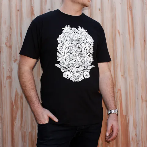 Man wearing a black t-shirt printed with a white totemic owl mask illustration in bold line work