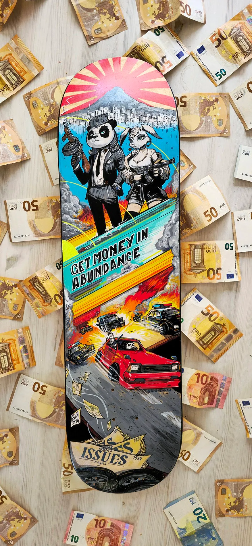 Painted skateboard featuring an armed panda and rabbit above a fiery police car chase, surrounded by Euro banknotes
