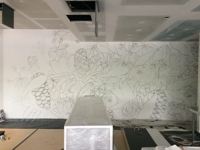 In-progress mural showing sketched outlines of large flowers, leaves and botanical elements on a wide white wall