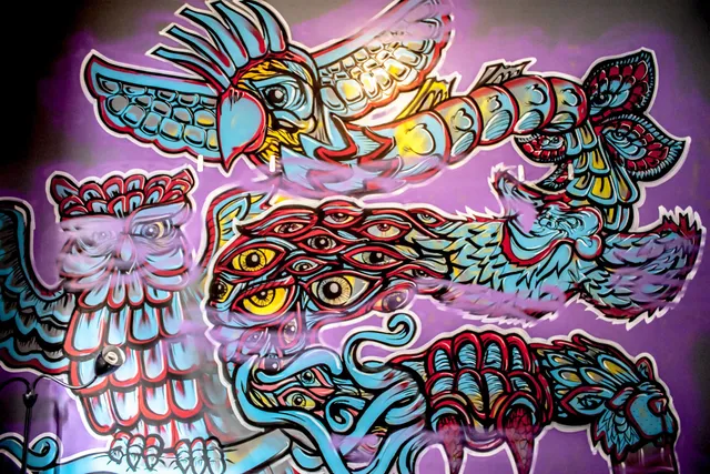 Psychedelic mural of totemic animals including an owl, cockatoo, panther, and a creature covered in eyes