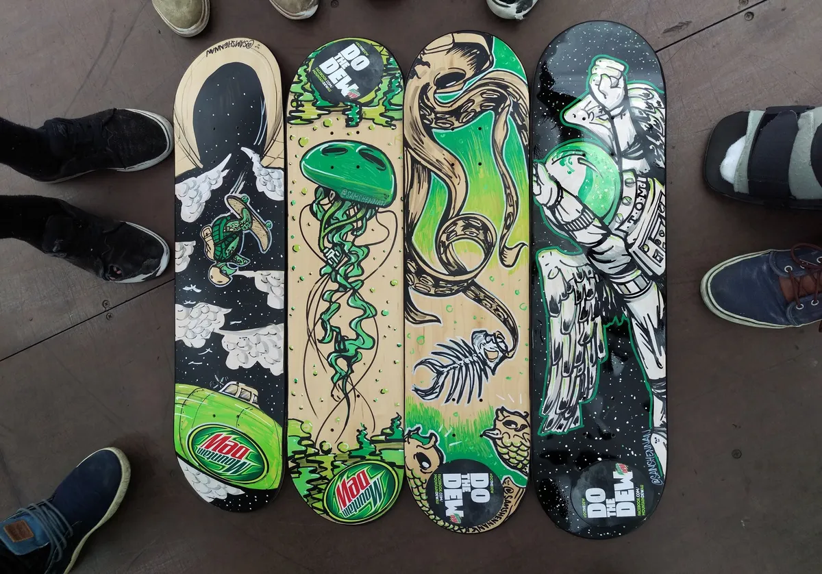 Four painted skateboards with Mountain Dew themes featuring a skating turtle, green jellyfish, tentacle, and astronaut