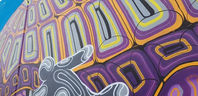 Mural detail of a psychedelic tortoise shell pattern in purple, yellow, and orange with bold grey line work