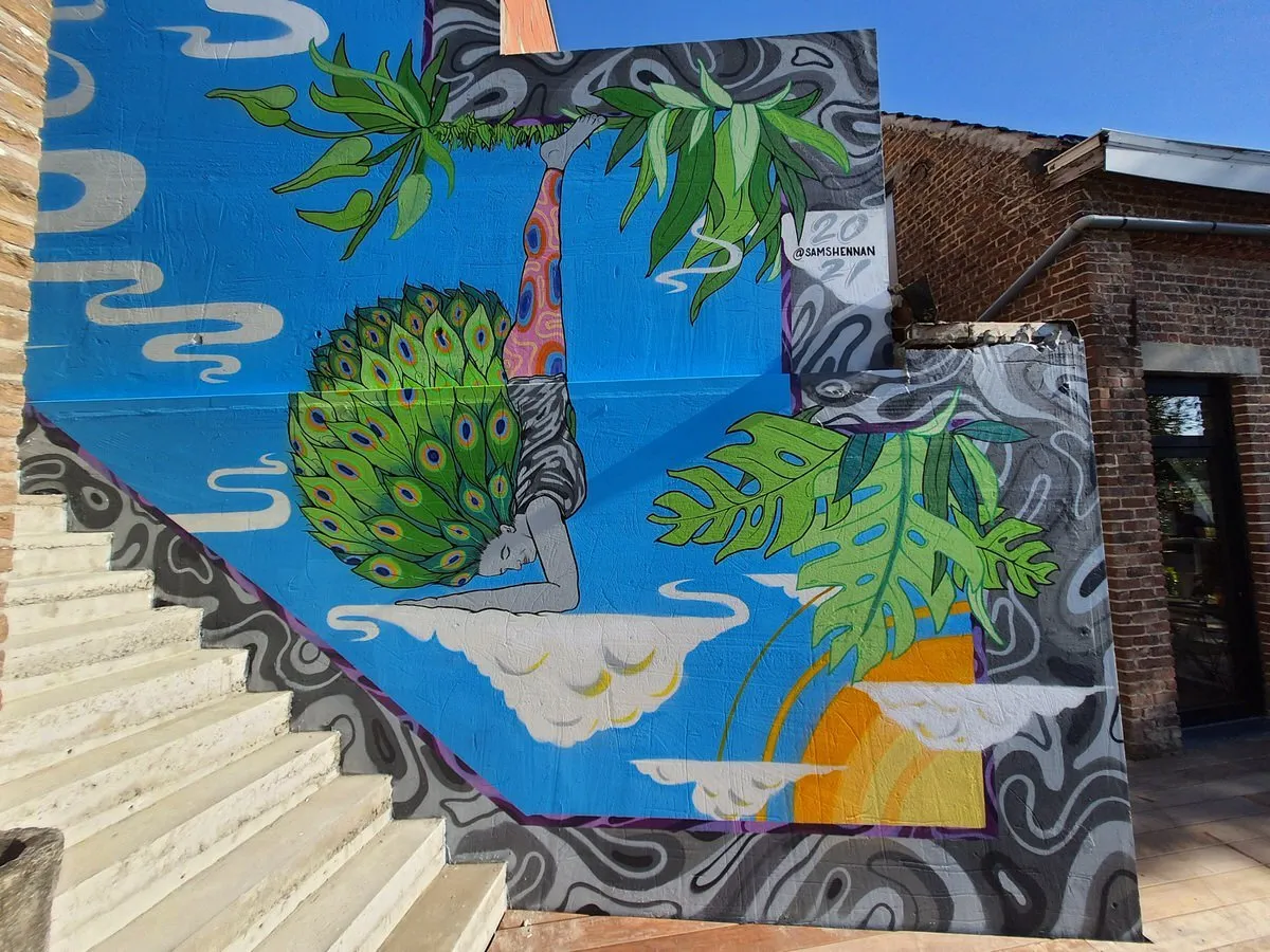 Mural of a figure in a forearm stand on a cloud with peacock feathers for hair, surrounded by large green leaves