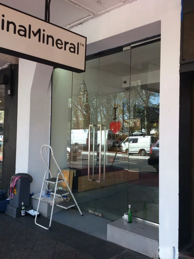 Window mural in progress at an Original Mineral storefront, featuring a step ladder and paint supplies