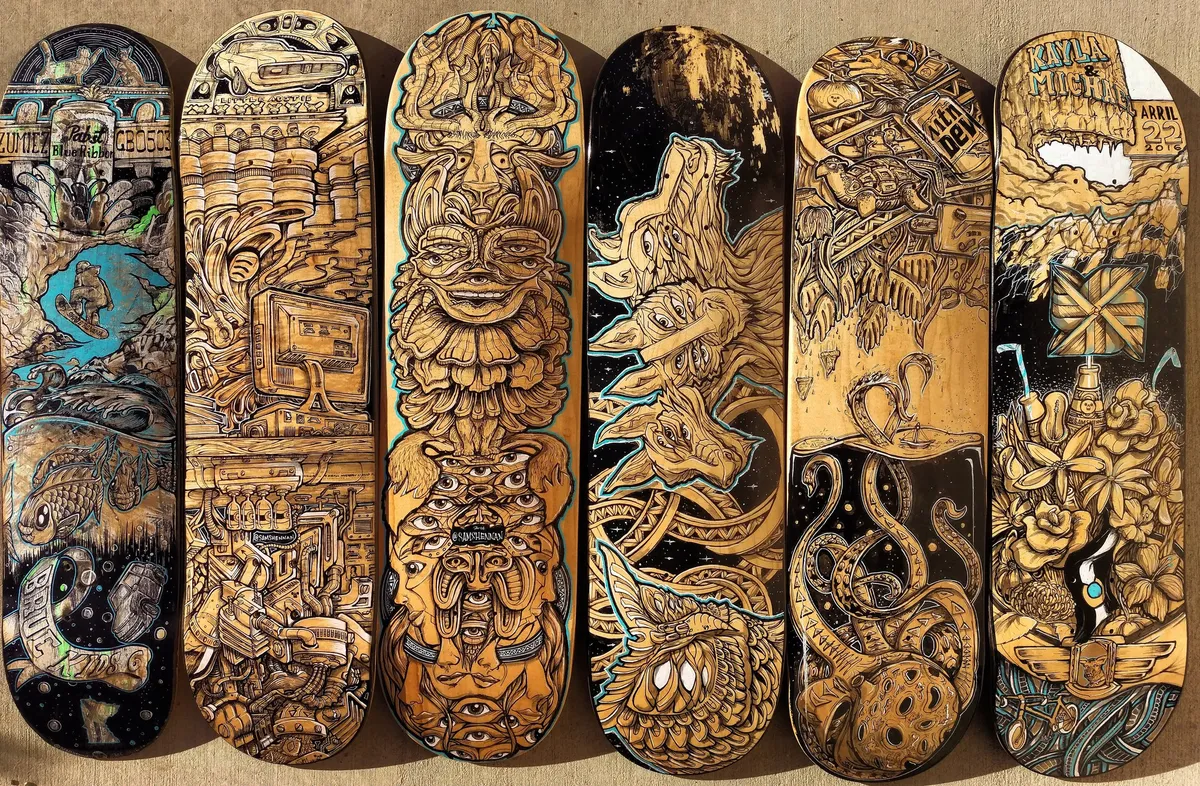 Six painted skateboards featuring intricate, psychedelic black line art of multi-eyed totemic faces and tentacles